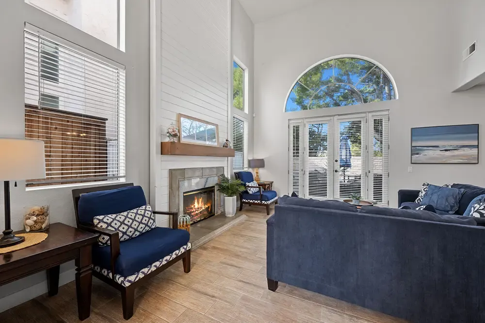 Living room with a fireplace, blue sofas and an arched window at a Wings home in Vista